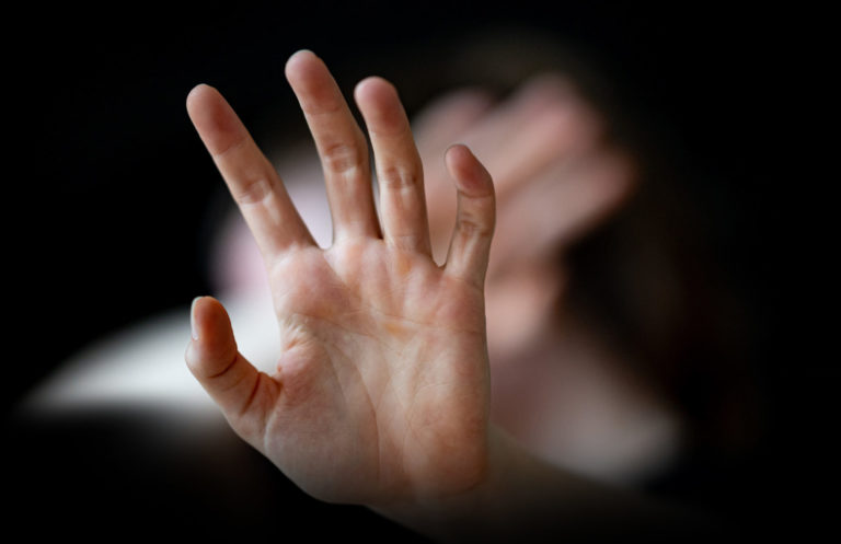 Frau hält sich schützend die Hände vor den Körper.