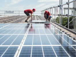 Klimaschutz: Darum geht’s beim Stromgesetz Zwei Männer montieren Solarkollektoren auf einem Dach.