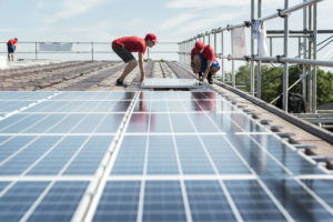 Zwei Männer montieren Solarkollektoren auf einem Dach.