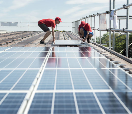 Klimaschutz: Darum geht’s beim Stromgesetz Zwei Männer montieren Solarkollektoren auf einem Dach.