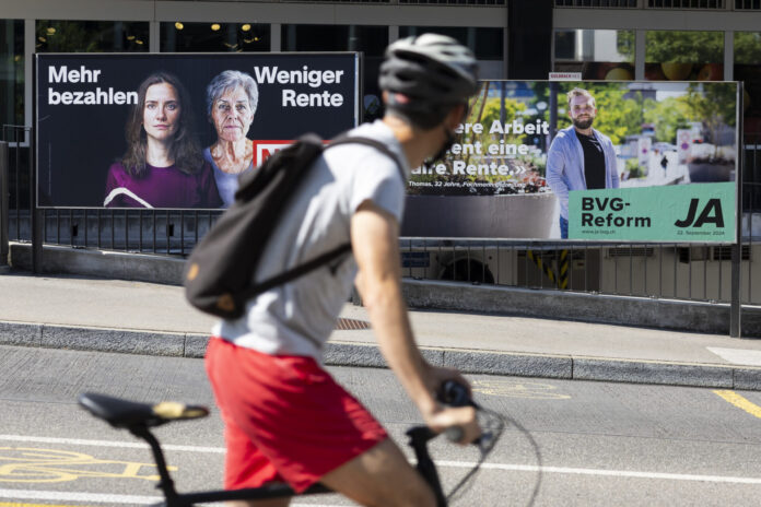 Plakate vom Ja- und Nein-Lager der BVG-Vorlage am Strassenrand. Im Vordergund ein Fahrradfahrer, der die Plakate anschaut.