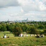 Personen in Park mit Skyline von London im Hintergrund.