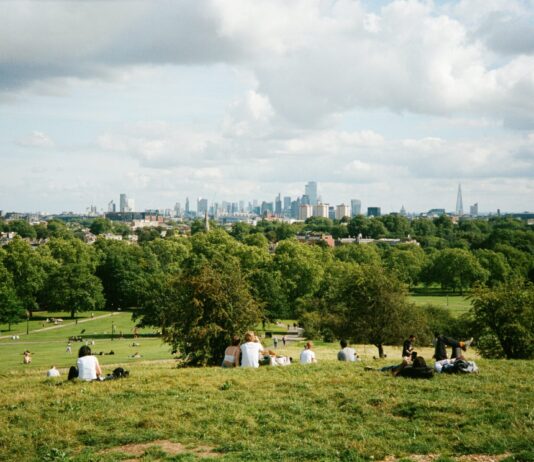 200 britische Unternehmen führen 4-Tage-Woche ein Personen in Park mit Skyline von London im Hintergrund.
