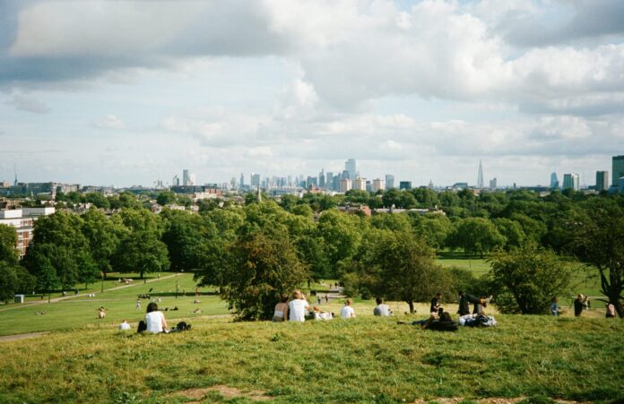 Personen in Park mit Skyline von London im Hintergrund.