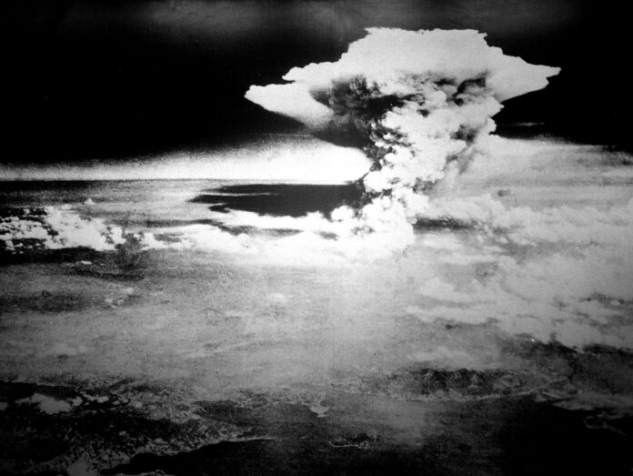 Schwarzweiß-Luftaufnahme: Eine mächtige Pilzwolke steigt über Hiroshima auf.