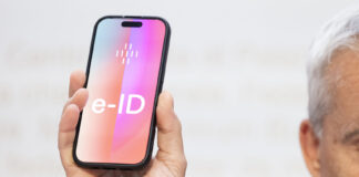Öffentliche e-ID wird unabhängig von Tech-Konzernen Ein Mann hält ein Smartphone hoch, auf dessen Bildschirm gross ‹e-ID› steht. Die Darstellung symbolisiert die geplante elektronische Identität der Schweiz