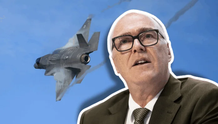 Collage aus einem Porträt eines Mannes in Anzug, Hemd, Krawatte und Brille, der spricht, vor blauem Himmel und einem dahinter in steilem Flug gezeigten Kampfjet (F-35).