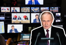 Anti-SRG-Initiative: Russland mischt mit In einer schwach beleuchteten Video-Regie steht im Vordergrund ein Multimedia-Mischpult, dahinter sind mehrere Kontrollmonitore zu sehen, die Aufnahmen einer Medienkonferenz des Bundesrats zur Anti-SRG-Initiative (Tische, Redner und Schweizer Flaggen) zeigen. Darauf überlagert ist Wladimir Putin, ein Mann in dunklem Anzug und Krawatte, der hinter einem Pult mit zwei Mikrofonen steht und offenbar zu einem Publikum spricht.